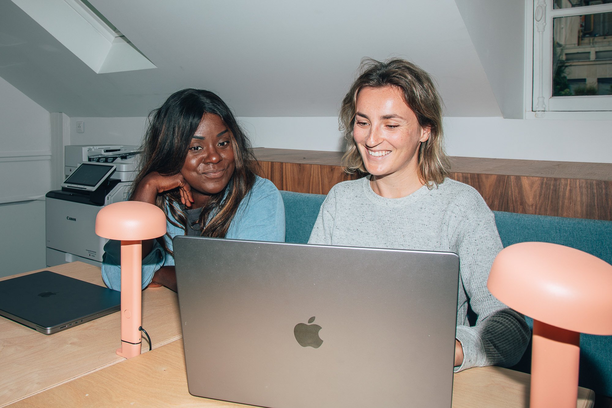 Two office workers looking at laptop and smiling 