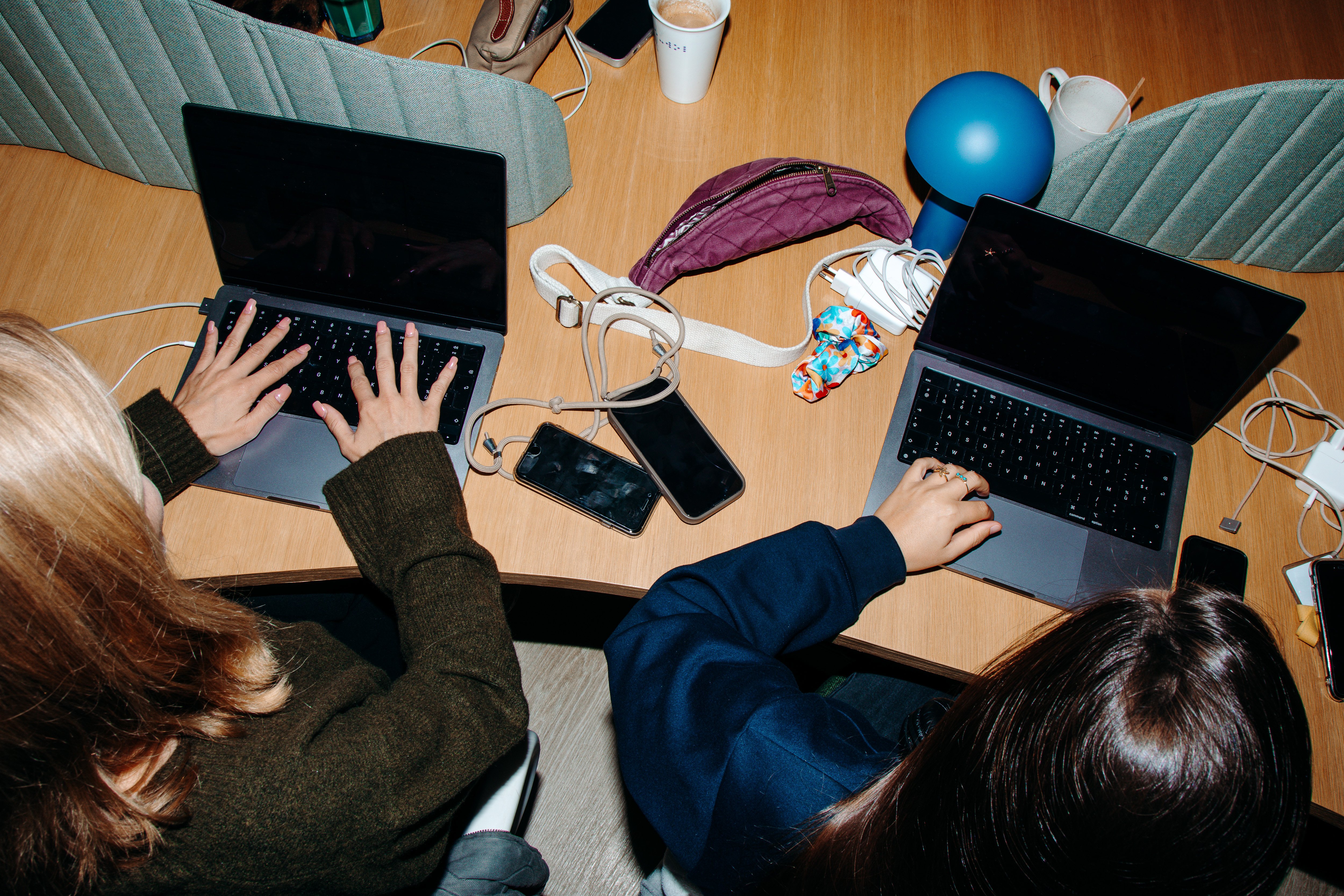 two people working on laptop facing away from camera