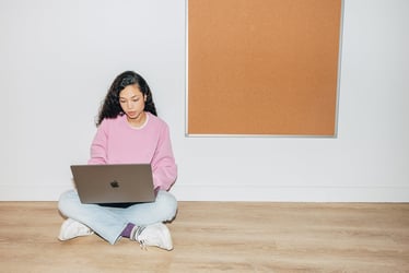Woman sitting cross-legged on the floor working remotely on a laptop