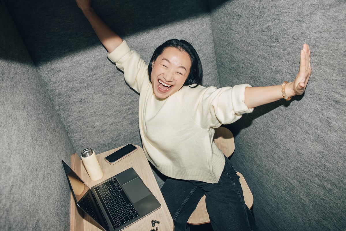 Femme souriante, les bras écartés, dans un espace de travail insonorisé.