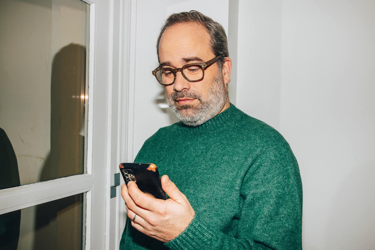 Homme consultant son téléphone près d'une fenêtre.