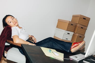 Femme détendue dans un bureau, les pieds posés sur un bureau devant un ordinateur.