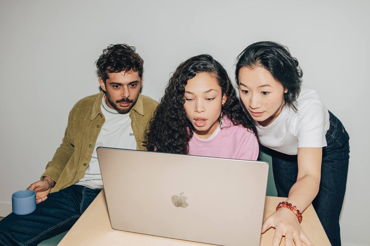Trois collègues qui regardent attentivement un écran d'ordinateur ensemble.