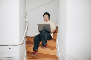 Femme travaillant sur un ordinateur portable assise dans un escalier.