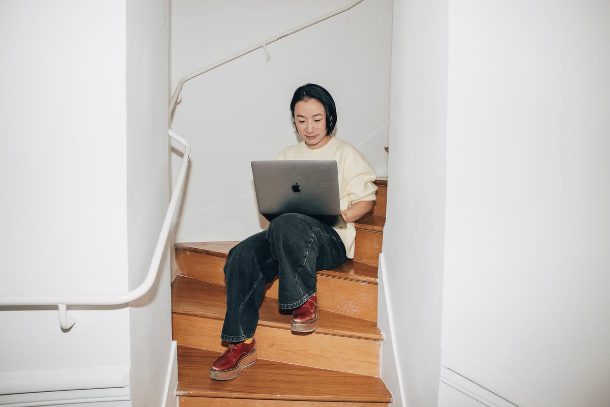 Femme travaillant sur un ordinateur portable assise dans un escalier.